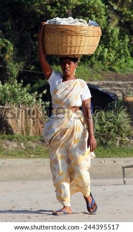 GOA, INDIA - FEB 20, 2014: Indian woman with big basket on her head. In India, that\'s a popular way to bring heavy things