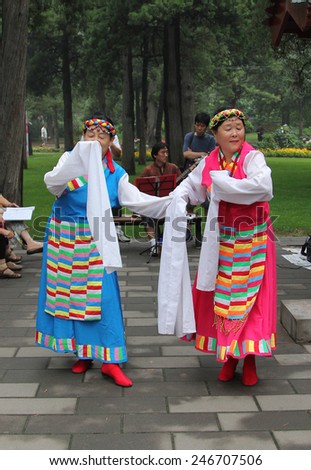 BEIJING, CHINA - JUL 17, 2011: Chinese women dancing in national costumes in Jingshan park, near Forbidden City. It\'s popular tradition among the Chinese people to engage in traditional arts outdoors
