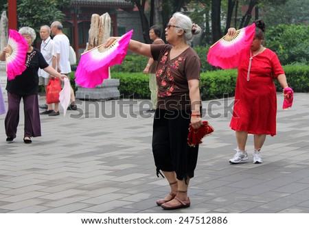 BEIJING, CHINA - JUL 17, 2011: Chinese elderly women dancing with fans in Jingshan park. Tai Chi, Wushu and other health practices outdoors - this is very popular activity among all ages in China