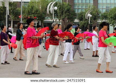 YINCHUAN, NINGXIA, CHINA - JUL 11, 2011: Chinese women dancing with fans on city square. Tai Chi, Wushu and other health practices outdoors - this is a very popular activity among all ages in China