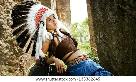 Native american girl , Indians in traditional dress, standing  to the stone slabs. American Indian girl