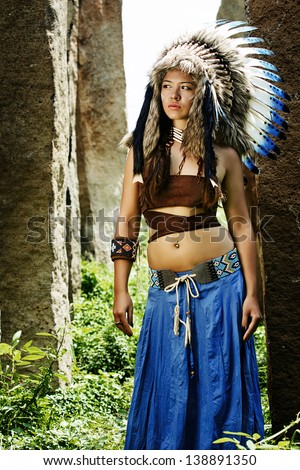 native american, indians, in traditional dress stands tall in a grove of stone. American Indian Girl