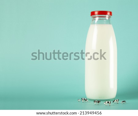 Milk bottle with cows on color background