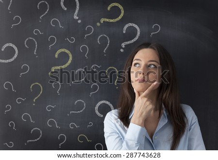 Businesswoman and question mark drawn in chalk on blackboard