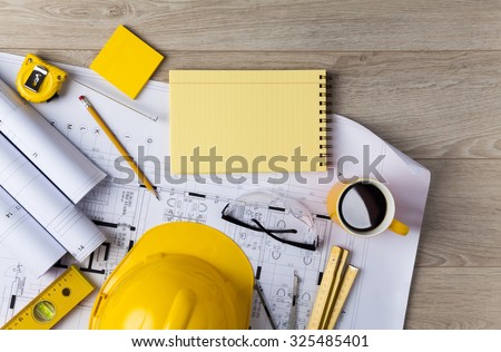 Blueprints, Hardhat, Glasses, Stickers, Construction level, Pen and Coffee in architecture office