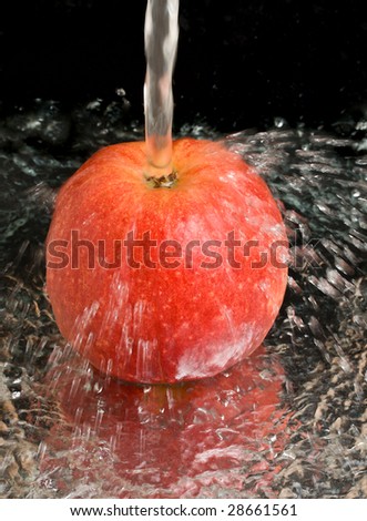 red apple under water stream on black