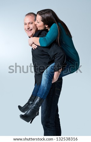 Happy young man giving a piggyback ride to her wife against white background