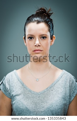 Young Woman with Serious Expression over a Grey Background