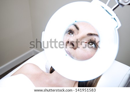 woman in a beauty clinic observed by magnifying glass
