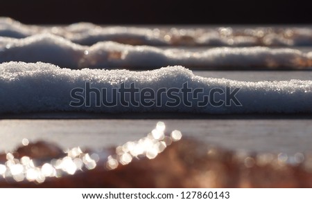 Snow and Ice melt on a forest bench under the spring sunlight