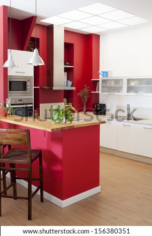 Modern kitchen interior with red walls and white furniture and bar at the foreground