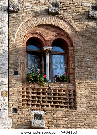 An old window on house in La Cisterna square in city of San Gimignano. Very good example of medieval construction with archs and columns.