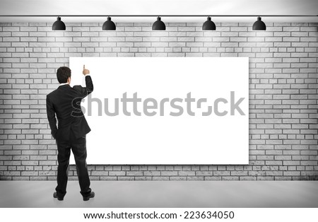 businessman looking empty poster on brick wall