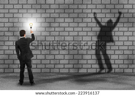 businessman holding idea bulb with businessman success shadow on wall in financial concept