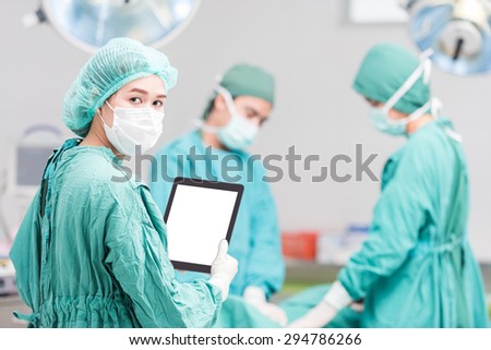 Young female woman nurse doctor surgeon using tablet computer with Surgical team team at operating room. looking at camera ,clipping path on tablet computer monitor