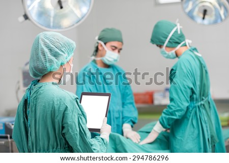 Young female woman nurse doctor surgeon using tablet computer with Surgical team team at operating room. selective focus on tablet computer , clipping path on tablet computer monitor