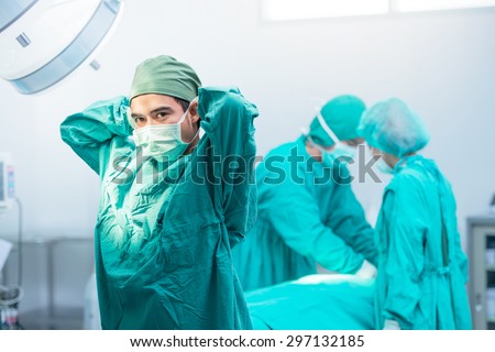 Male surgeon tying mask at operating room