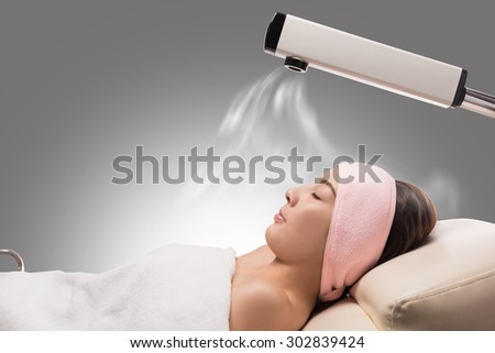 Beauty treatment of face skin with ozone facial steamer in spa center , asian women facing the steam. Steam for smooth skin