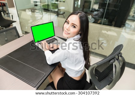 Beautiful business woman using a laptop computer at office, smiling face, clipping path on screen