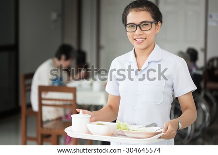 elderly and nurse or carer, Helper Serving Senior Woman With Meal In Care Home