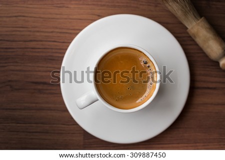 cup of fresh espresso with cleaning blush of coffee machine on table, view from above