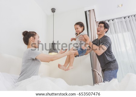 Happy loving family. Young mother and father are playing with daughter in the bedroom. parents are having fun on the bed.
