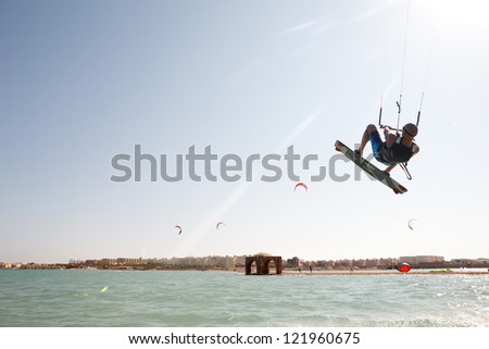 Kiteboarder enjoy surfing in blue water and jumps high in the air.