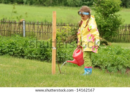 Little girl watering apple tree with watering pot