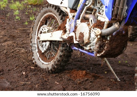 Close-up of muddy rear wheel and engine of dirt bike, details
