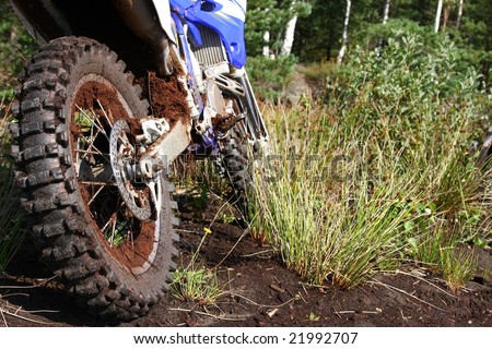 Close-up of muddy rear wheel and engine of dirt bike, details