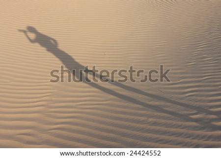 Shadow in dunes with a man drinking water