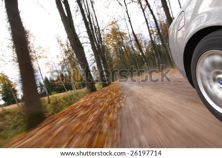 Car driving on country road. Autumn scene, low angle, motion blur.