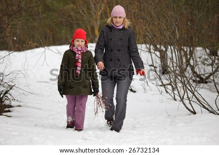 Mother and daughter walking in forest and picking pyssy-willows