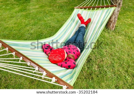 Little girl having a rest in a hammock in a garden