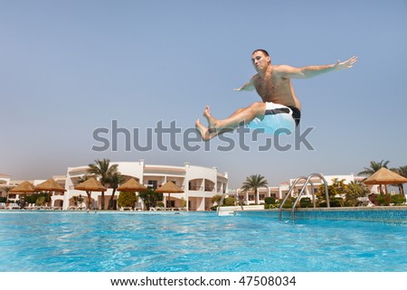 Man jumping in swimming pool.  Low angle view from the swimming pool.