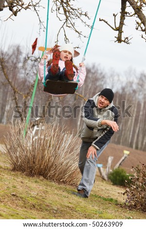 Father swinging daughter in a garden. Fun in early spring.