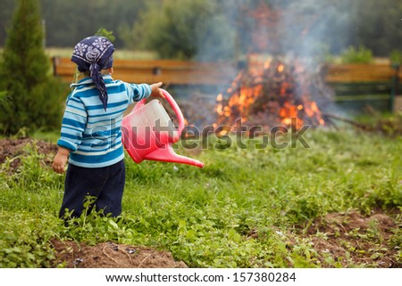 Boy at big fireplace with big watering can helping fight fire