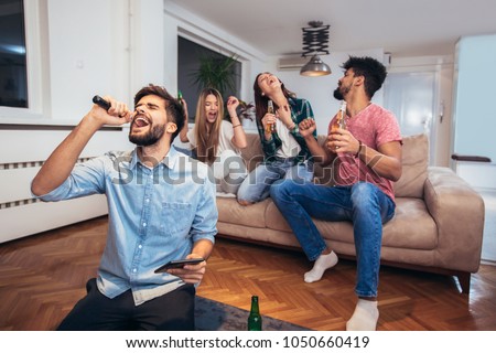 Group of friends playing karaoke at home. Concept about friendship, home entertainment and people