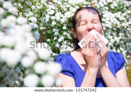 Allergic woman sneezing in handkerchief