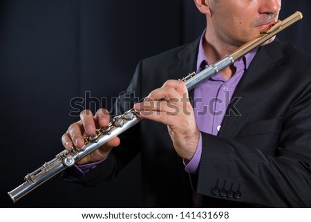 professional flutist musician playing flute on black background