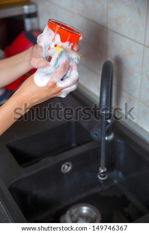 Washing of the dishes - woman hands rinsing dishes