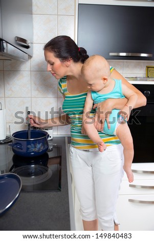 mother with a newborn baby cook food in the kitchen