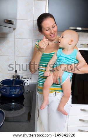 mother cook food in the kitchen and feed the baby