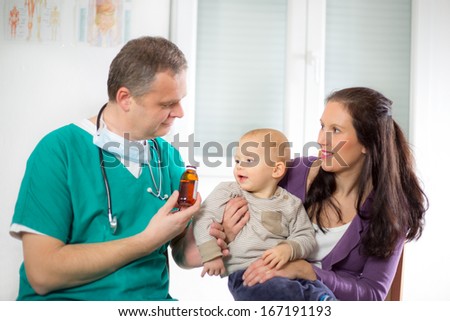 pediatric doctor giving pills bottle to mother with baby