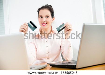 Smiling corporate woman showing her cash card  and credit card to the camera.