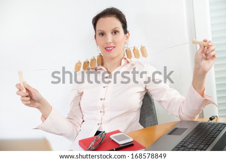 young businesswoman with neck pain sitting at office desk and uses and uses mas-sager