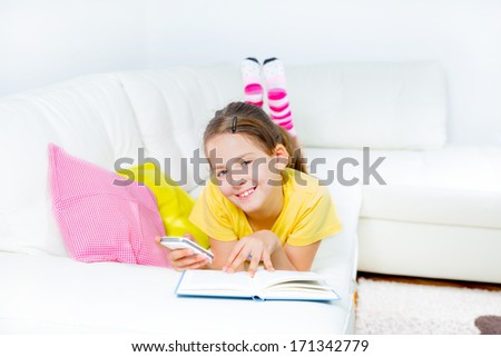 little girl with smart phone and book at home