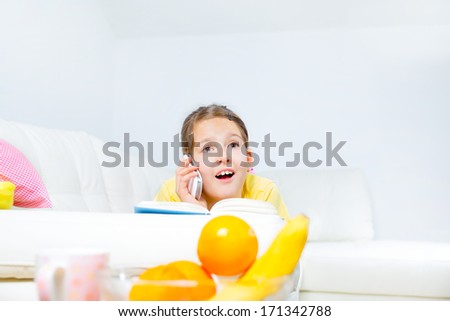little girl with smart phone and book at home