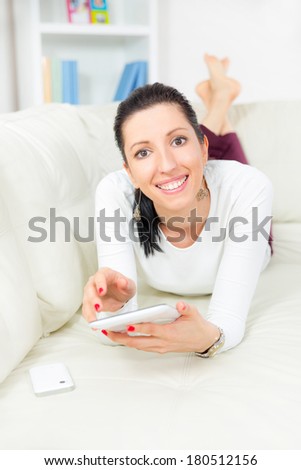 Smiling young woman with tablet pc laying on sofa