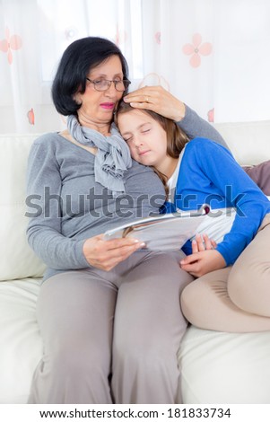 Grandmother reading magazine, granddaughter sleeping